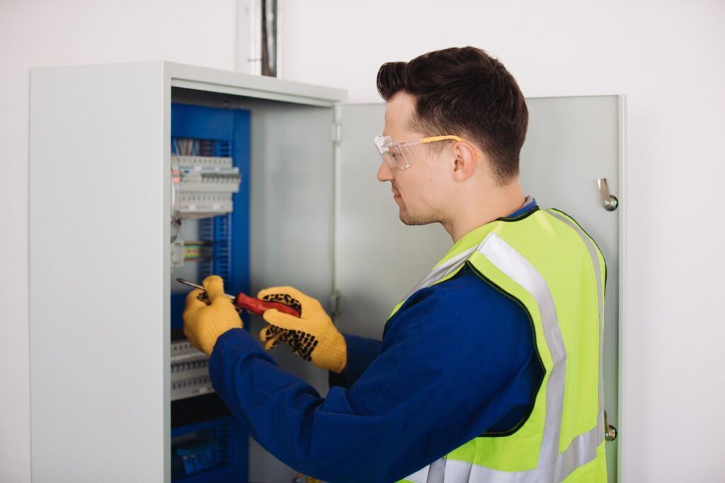 Electrician answering service for electrical contractors: electrician working on an electrical panel