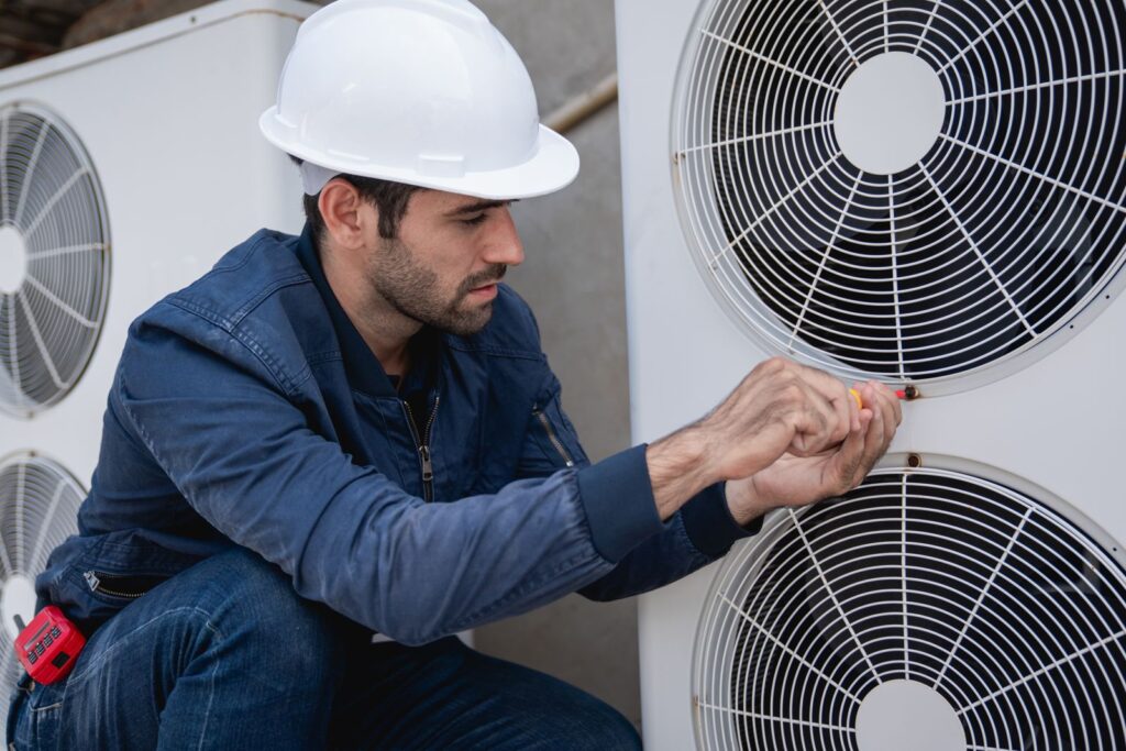 HVAC answering service for HVAC contractors: technician servicing an outdoor AC unit